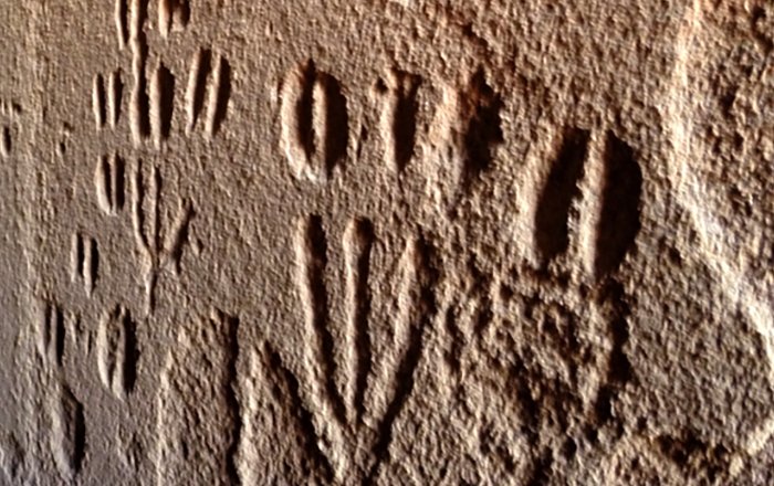 Hidden panel of the RAS 8 rock art site. The narrow corridor RAS 8-N, with engravings on both sides which extend as far inside as the lower exfoliated rock face; from the position of the photographer at the entrance, this is situated roughly three metres into the corridor (photograph: T. Lenssen-Erz).