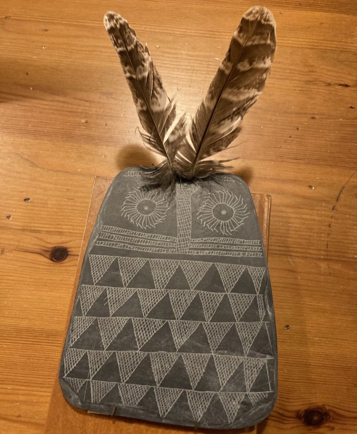 Replica of the Valencina Slate Plaque with inserted owl feathers on the two drilled holes at the top of the plaque. Credit: Juan J. Negro