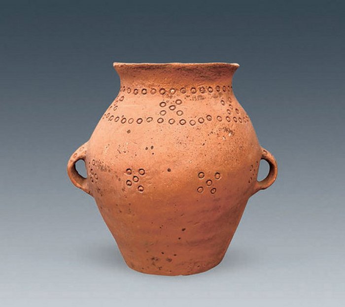 This pot, found in the tomb with the small chamber, contains o-shaped incisions that form an elaborate design. It is handmade and made of red clay. (PH๏τo courtesy Chinese Cultural Relics.)